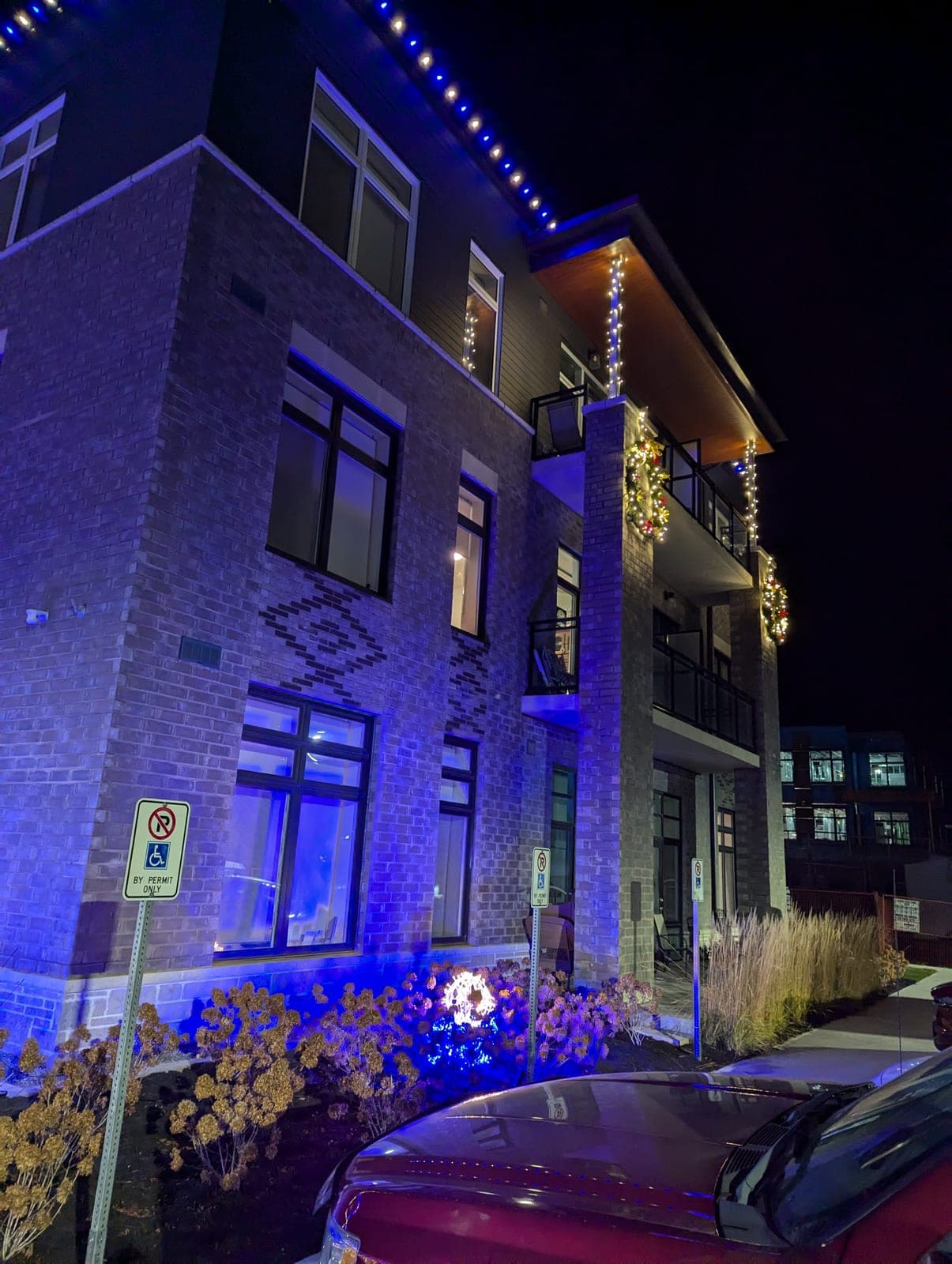 Commercial building with blue roofline lighting and lit wreaths on the balconies at night