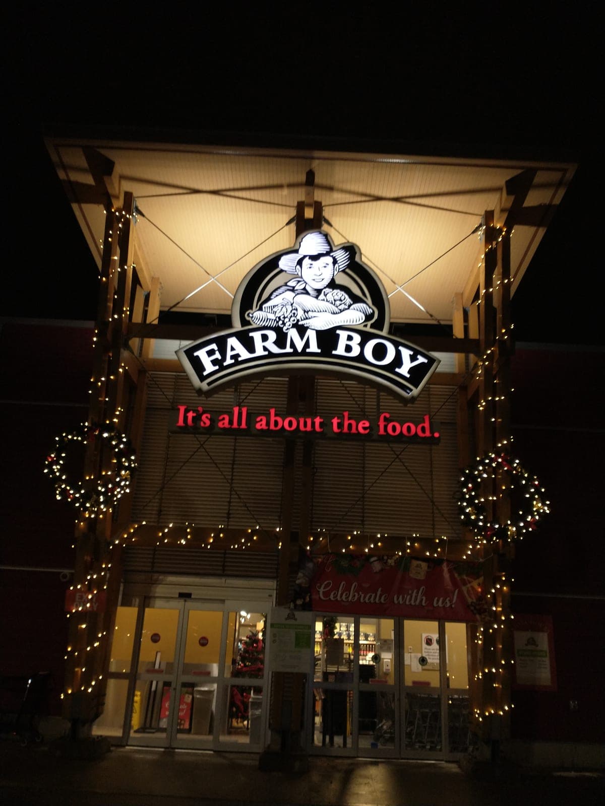 Commercial building entrance framed with warm-white Christmas lights, garland and lit wreaths