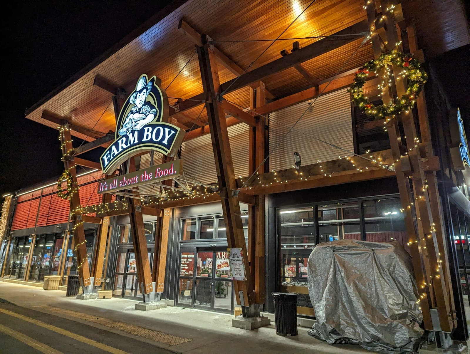 Commercial storefront entrance with warm-white Christmas lighting and a glowing wreath at night