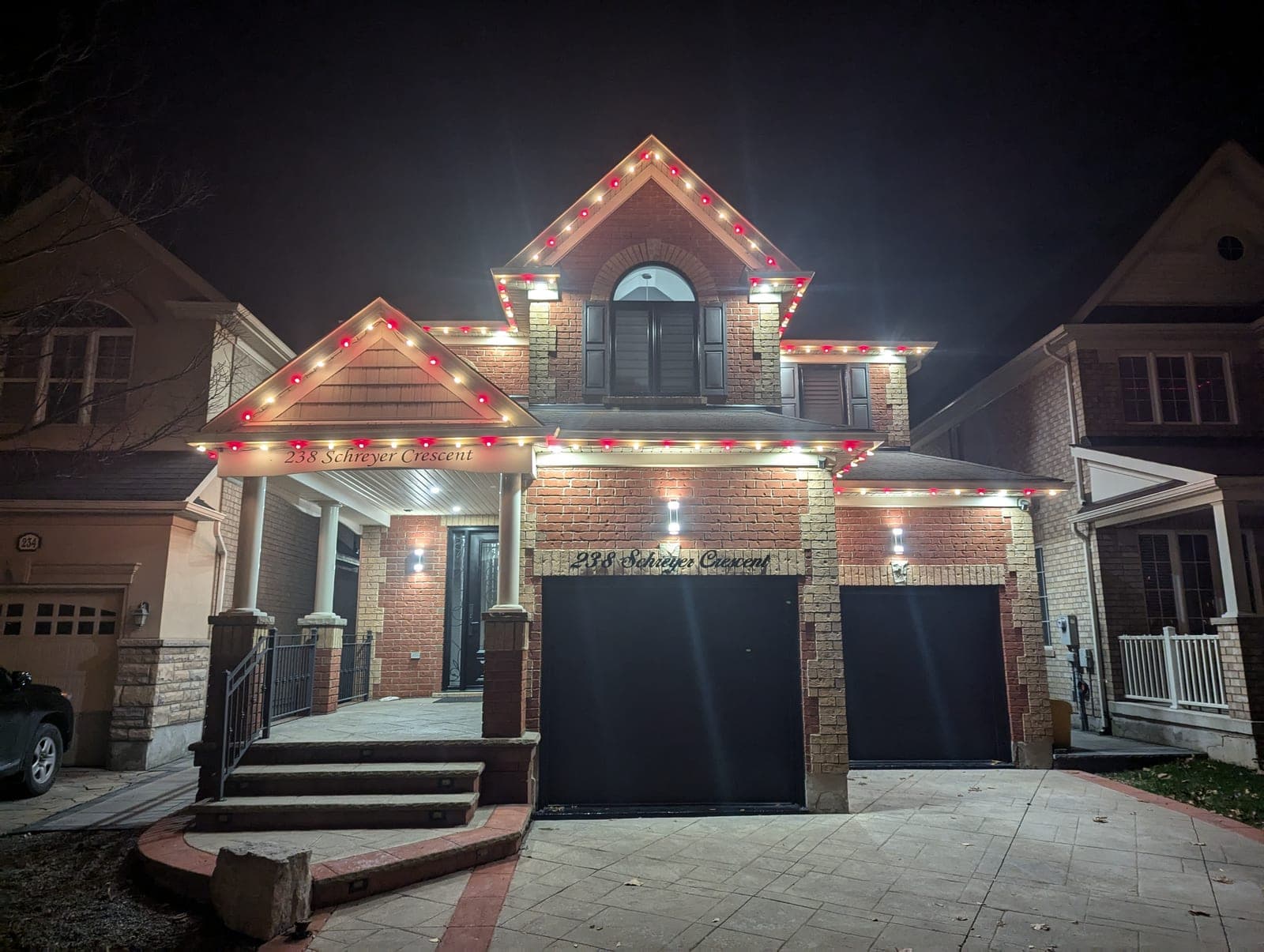 Comparison of a Hamilton area home lit with bold C9 bulbs along a warm brick roofline at dusk